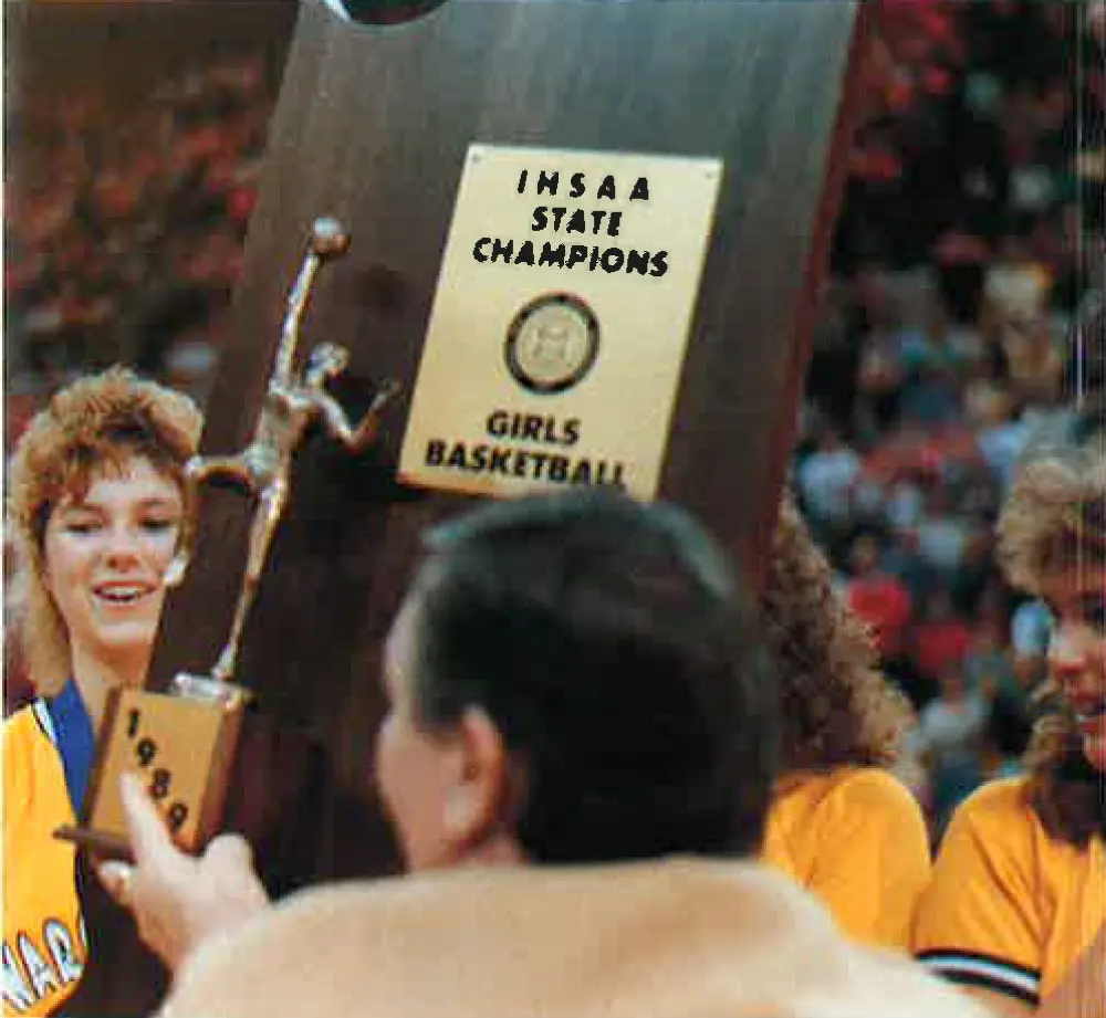 Smiling Warriorettes in gold reach for the IHSAA state champions girls basketball trophy, 1989