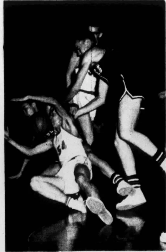 Newspaper photo: players in light and dark jerseys tangled up and falling to the floor