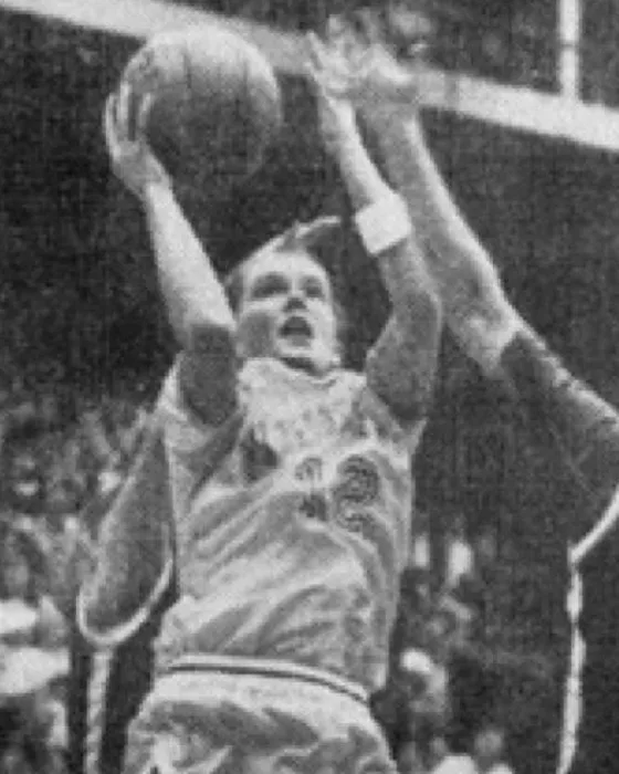 Patty Hutchinson going up for a shot over a defender in a white Warriorettes uniform